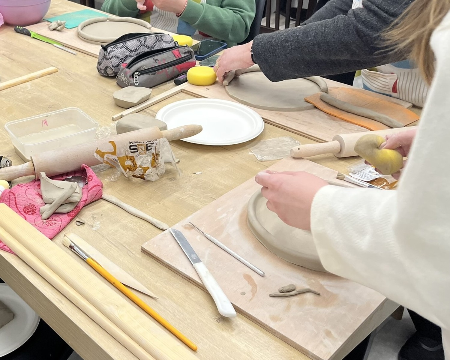 Hands shaping clay during a ceramic sculpture workshop at Arte Fino